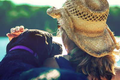 Woman in hat with dog against lake