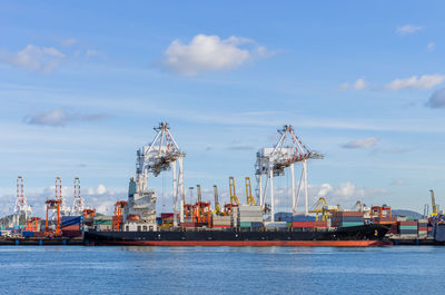 Cranes at commercial dock against sky