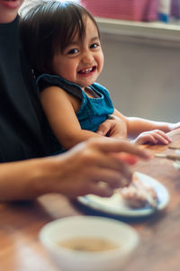 Portrait of cute girl sitting on table at home