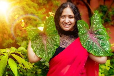 Portrait of a smiling young woman holding plant