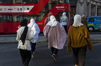 Rear view of people walking on road in city