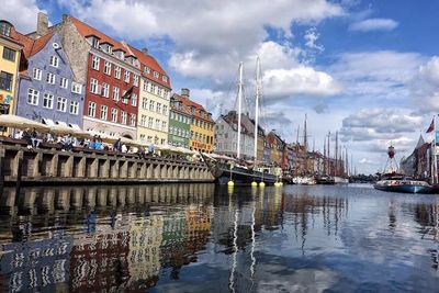 Boats in harbor against cloudy sky