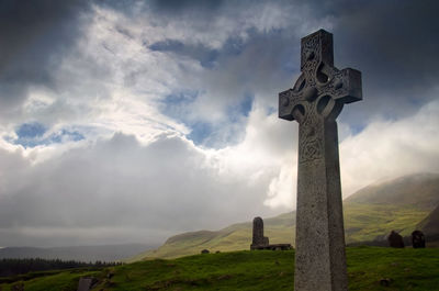 Cross at cemetery against sky