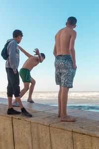 Rear view of shirtless man standing on beach