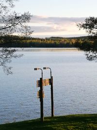Wooden post in lake against sky at sunset