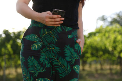 Midsection of woman using mobile phone outdoors