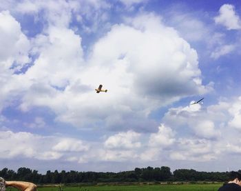 Low angle view of airplane flying against cloudy sky