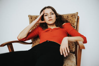 Portrait of young woman sitting on chair at home