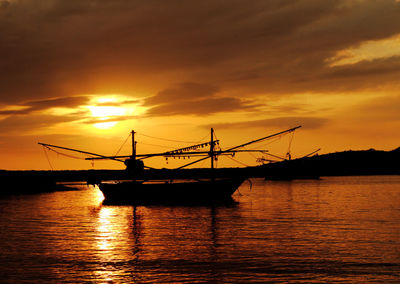 Silhouette ship in sea against sky during sunset