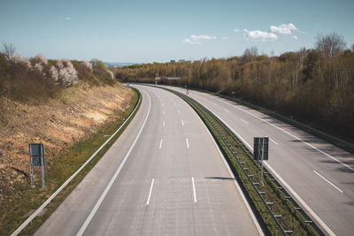 Empty road along landscape and trees against sky