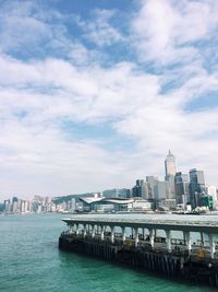 City at waterfront against cloudy sky