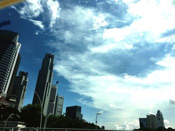 Low angle view of skyscrapers against cloudy sky