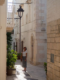 Woman standing by potted plants outside building