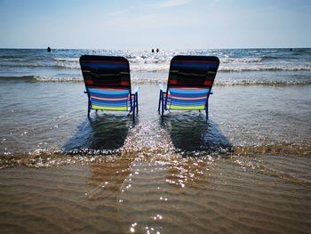 Lounge chairs on beach against sky