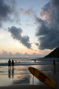 Silhouette people at beach against sky during sunset