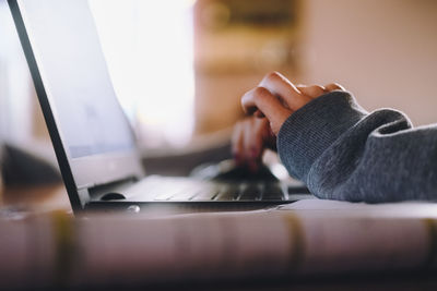 Close-up of man using laptop on table