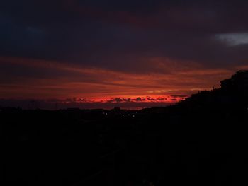 Silhouette landscape against dramatic sky during sunset