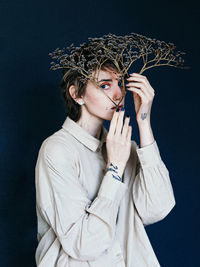 Portrait of young woman standing against black background