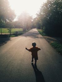 Rear view of boy walking on road