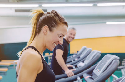 Side view of people walking on treadmills in gym