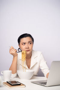 Young woman using phone while sitting on table