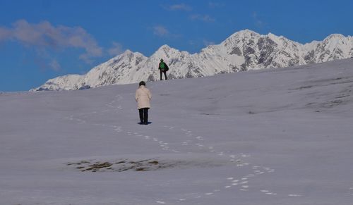 Rear view of woman walking on snow covered mountain