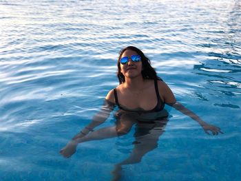 Portrait of woman wearing sunglasses swimming in pool