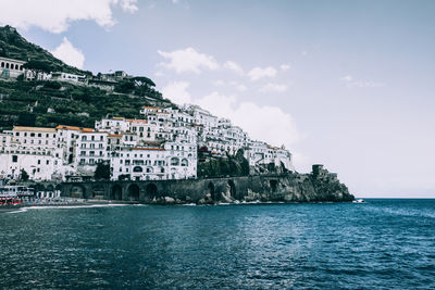 Scenic view of sea by buildings against sky