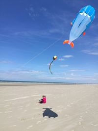 Kite flying over beach against blue sky