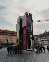 People walking on street in city against sky
