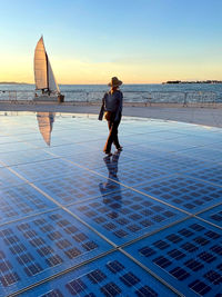 Rear view of woman walking over solar panel greeting to the sun located at zadar, croatia