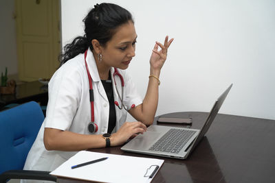Young woman using mobile phone while sitting on table
