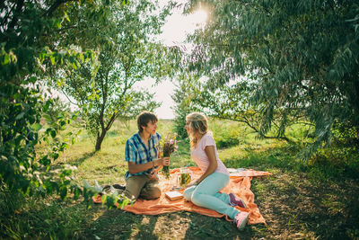 Rear view of friends sitting on tree