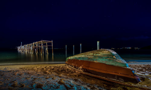 Abandoned boats moored in lake against sky at night