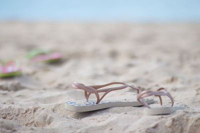 Close-up of flip-flop on sand at beach against sky