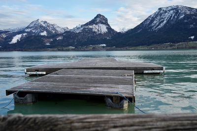 Pier on lake against snowcapped mountains