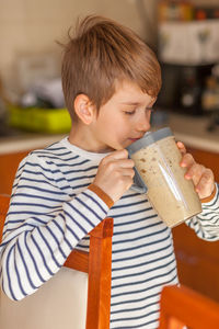 Smiling boy holding drink at home