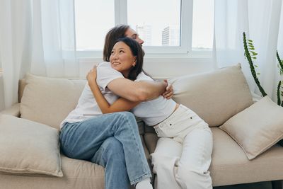 Young woman using laptop while sitting on sofa at home