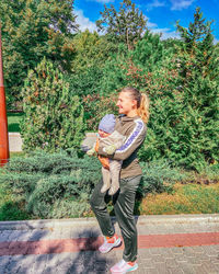 Woman standing by plants against trees