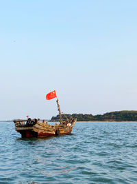 Fishing boat in sea against clear sky