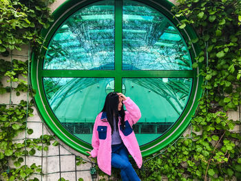 Young lady in pink jacket at the rooftop of warsaw university library near green round window 