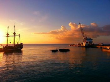 Sailboats in sea at sunset