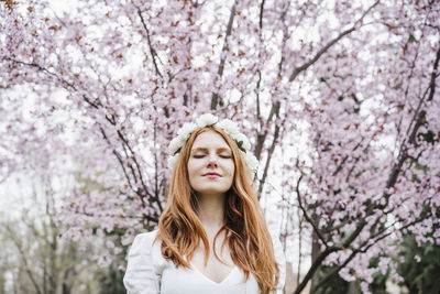 Portrait of young woman with cherry blossoms in spring