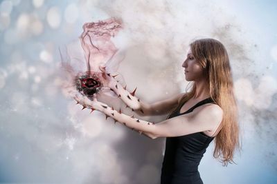 Digital composite image of young woman holding rose