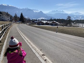 Rear view of person on road against snowcapped mountain