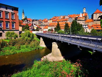 Bridge over river amidst buildings in city against sky