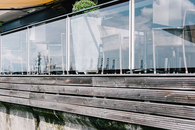 Empty chairs and tables at restaurant with crane reflections on glass railing