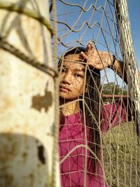 Portrait of young woman seen through goal post on soccer field