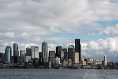 City at waterfront against cloudy sky