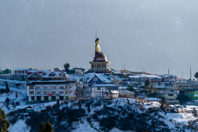 Statue in city against sky during winter